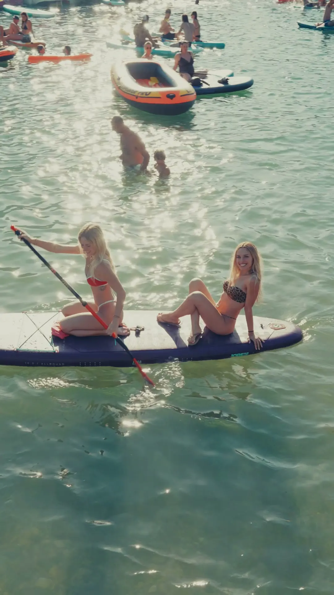 Due ragazze su una tavola da SUP nell'acqua limpida del lago